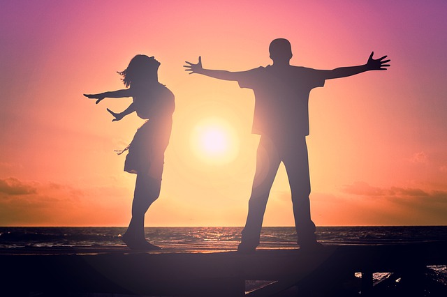 Dos jóvenes bailando sobre la arena en una puesta de sol